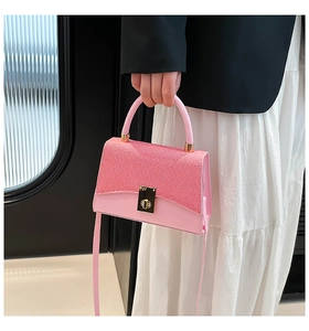 Detail of pink structured handbag with woven texture and gold twist lock in lifestyle view