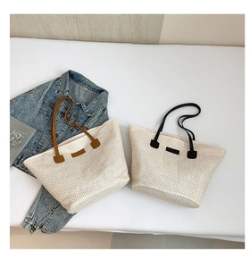 Gros plan de sacs cabas en paille tressée avec anses en cuir marron et noir sur fond blanc