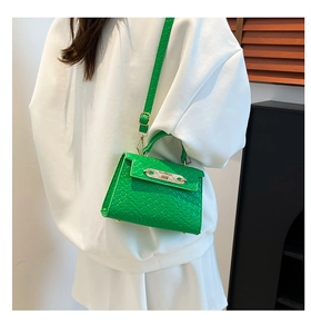Bright green crossbody bag with woven texture and gold twist lock shown on model