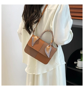 Detailed side view of brown crossbody bag with plaid scarf handle and textured patchwork