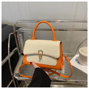 Detail of orange leather and cream woven texture handbag with golden horseshoe buckle