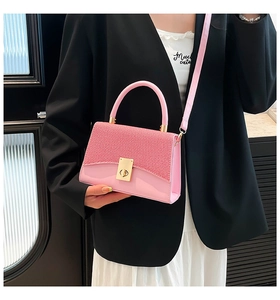 Detail of pink crossbody bag with gold rectangular clasp and textured woven flap