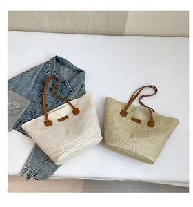 Détail de sacs fourre-tout en paille tissée avec lanières en cuir brun et texture naturelle