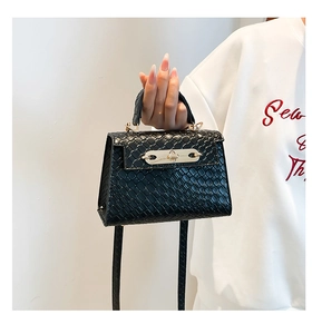 Detail of black woven texture leather bag with elegant golden metal twist lock closure