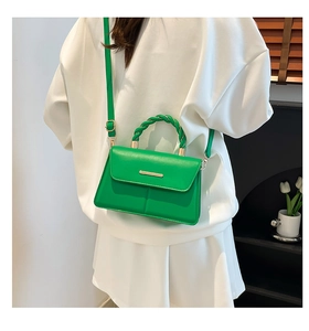Détail du sac bandoulière vert avec poignée tressée et garniture dorée sur mannequin