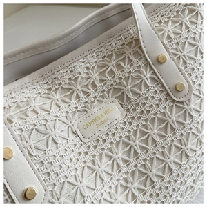 Detail of white hollow woven tote bag featuring gold rivets and elegant leather trim