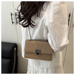 Detail of khaki woven texture square bag with gold chain strap and metal clasp closure
