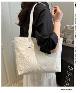 Close-up of white woven leather tote bag texture and long shoulder strap detail