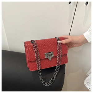 Détail d'un sac bandoulière rouge avec texture tissée et chaîne métallique