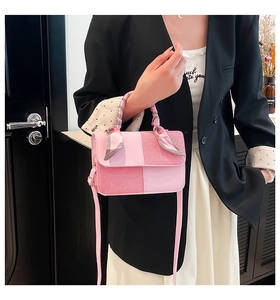 Pink patchwork handbag with scarf handle and crossbody strap held by model indoors