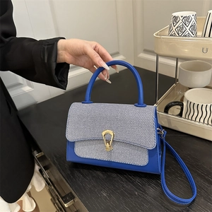 Chic blue and white textured crossbody bag with golden horseshoe clasp and top handle