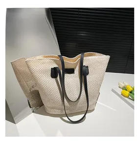 Gros plan du sac seau tissé crème avec des lanières en cuir noir et détails texturés