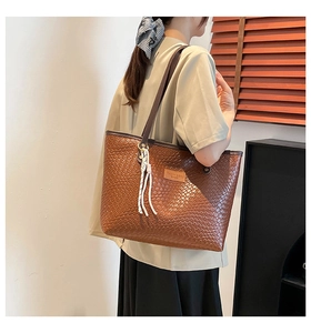 Gros plan du sac cabas tissé marron avec étiquette en cuir et pompon blanc