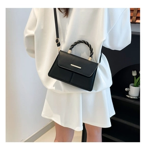 Détail d'un sac à rabat noir chic avec une poignée en corde torsadée et accents dorés