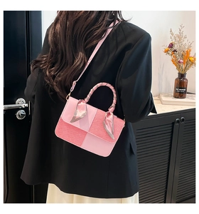 Detail of pink patchwork crossbody bag featuring silk scarf handle over a black blazer