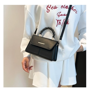 Détail du sac à main en cuir noir mat avec boucle dorée et poignée torsadée bicolore