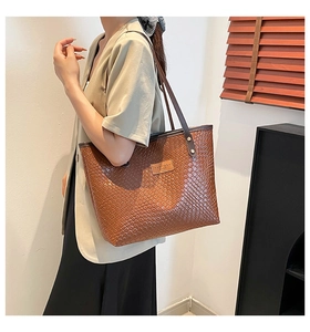 Détail d'un sac cabas tissé marron avec étiquette de marque et fines bretelles doubles