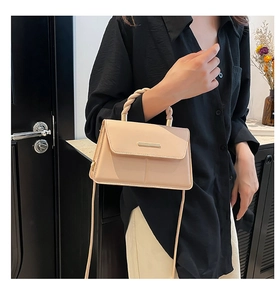 Détail du sac beige avec poignée en corde torsadée et décoration métallique élégante