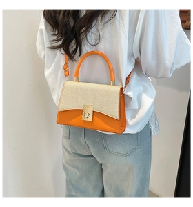 Detail of a chic orange and beige woven small square bag with golden metal buckle