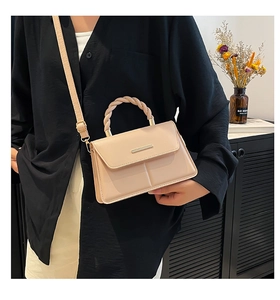 Détail d'un sac à bandoulière élégant avec poignée tressée et garniture en métal doré