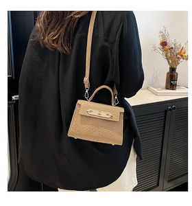 Detail of khaki crocodile-embossed Kelly-style bag with golden hardware and rotating lock