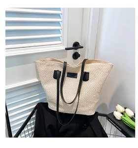 Détail du sac cabas beige tressé avec lanières en cuir noir et étiquette de mode décor