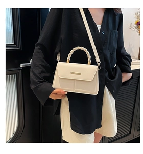 Détail du sac bandoulière blanc crème avec poignée tressée et barre en métal décorative