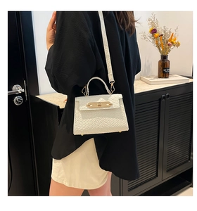 Close-up of cream textured leather mini bag with gold buckle and chain strap on model