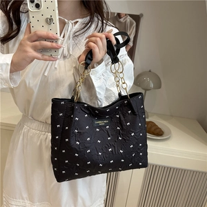 Fashion black tote bag with white bows and gold chain shoulder strap shown on model