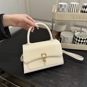 Detail of cream leather handbag with woven texture flap and golden horseshoe lock