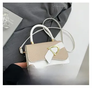 Close-up of beige and white patchwork crossbody bag with gold D-ring clasp detail