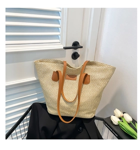 Détail du sac cabas en paille tressée avec anses en cuir marron et étiquette de mode