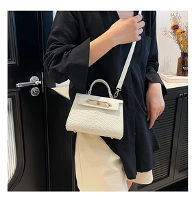 Mini cream crossbody bag with woven texture leather and gold bar lock on a model