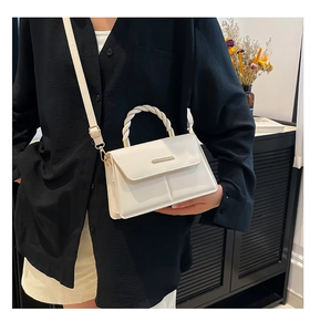 Détail du sac bandoulière en cuir blanc avec poignée tressée et garniture dorée