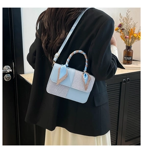 Side view of woman in black blazer carrying light blue paneled crossbody bag with ribbon handle