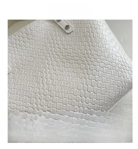 Detail of white woven leather texture with round metal rivets on a luxury handbag