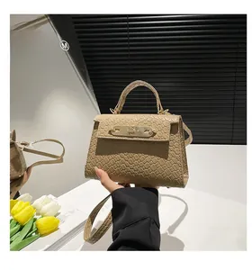 Detail of khaki woven texture handbag featuring gold hardware clasp and top handle