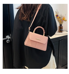 Détail du sac à bandoulière en cuir rose avec poignée tressée et fermoir métallique