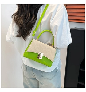 Detail view of contrast stitching canvas bag with green leather trim and gold lock