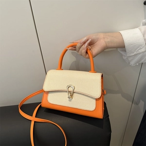 Detail of orange and beige handbag with horse-bit gold lock and woven flap texture