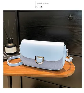 Détail du sac à rabat bleu avec texture cuir mélangé et boucle argentée en forme de D