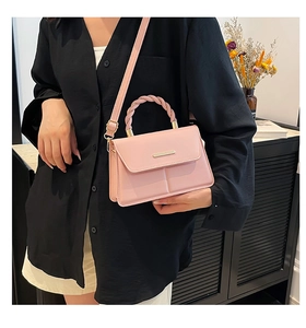 Détail du sac bandoulière en cuir PU rose avec une poignée tressée et une barre métallique dorée