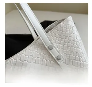 Macro view of woven leather texture and silver metal rivets on a white tote bag