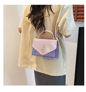 Dettaglio borsa con patta glitter rosa, corpo viola e logo SS dorato con nappa