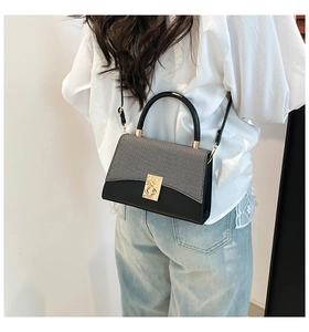 Detail showing the gray textured fabric and golden metal lock of this crossbody bag