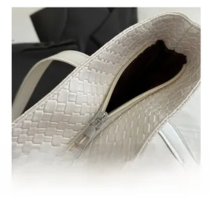 Close-up of smooth metal zipper and woven texture on beige faux leather tote bag