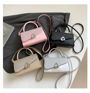 Flat lay of four sequined crossbody bags in pink, black, gold and silver with heart clasps