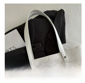 Detail of white embossed tote bag with reinforced handles and silver metal rivets