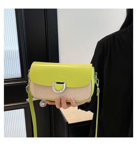 Détail de cuir vert néon et tissu tissé beige épissé sur un sac à bandoulière avec boucle en D