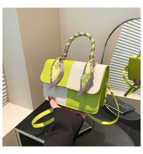 Detail of neon green and woven cream handbag with elegant silk scarf wrapped handle